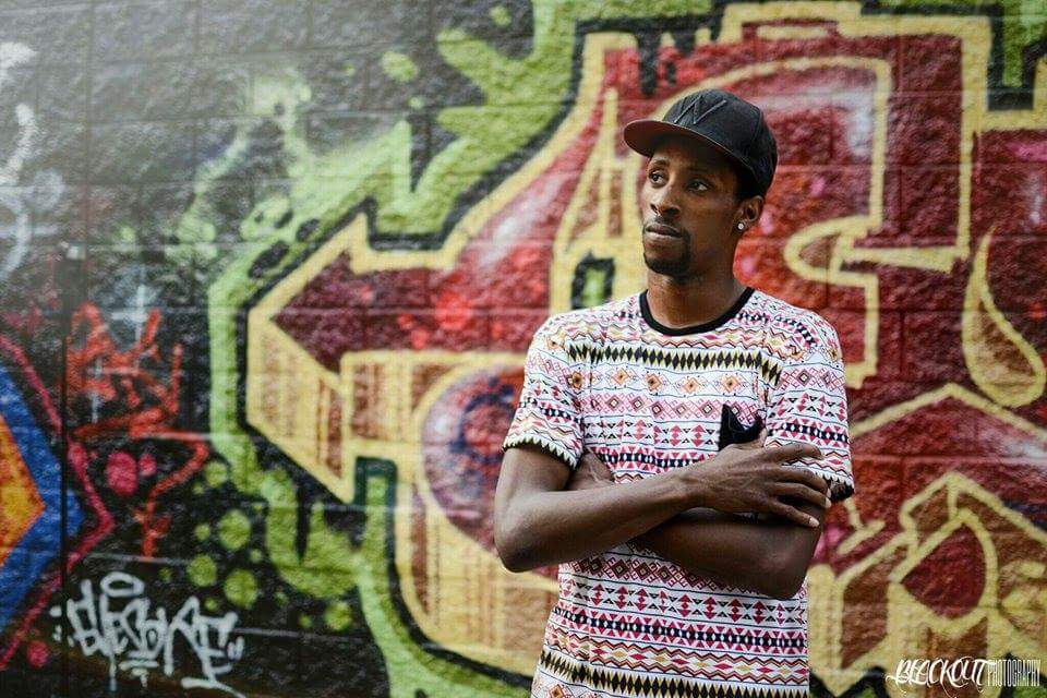 Taris Clemons standing with arms crossed in front of a graffiti mural