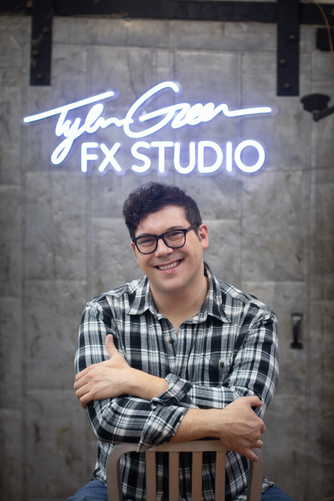 Tyler Green seated beneath a Tyler Green FX Studio neon sign